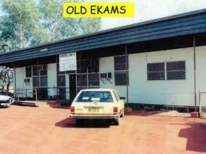 Historical photo of the old EKAMS building with a vintage vehicle parked out front.